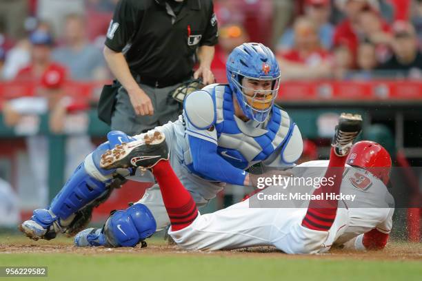 Joey Votto of the Cincinnati Reds slides safely into home as Tomas Nido of the New York Mets tries to catch an errant ball at Great American Ball...