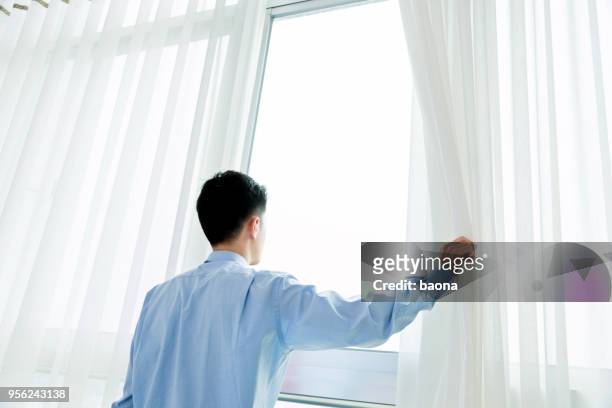 businessman at the window of hotel room - rear view hand window stock pictures, royalty-free photos & images