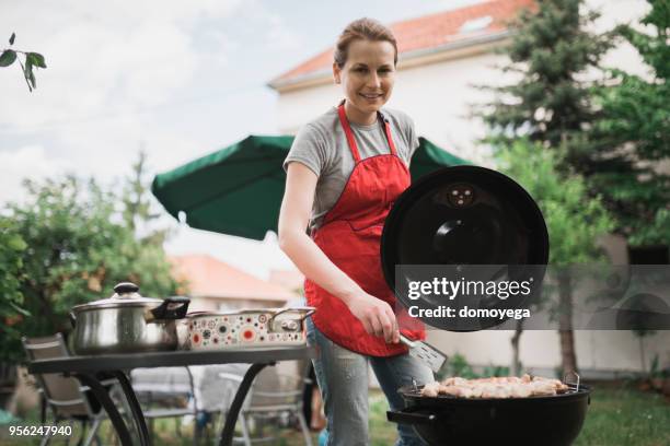 lächelnde frau eine gartenparty grillen vorbereiten - barbeque party woman stock-fotos und bilder