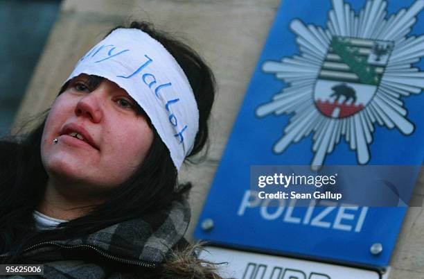 Young woman wearing a headband that reads: "Oury Jalloh" joins protesters blocking the entrance to the main police station during a demonstration...