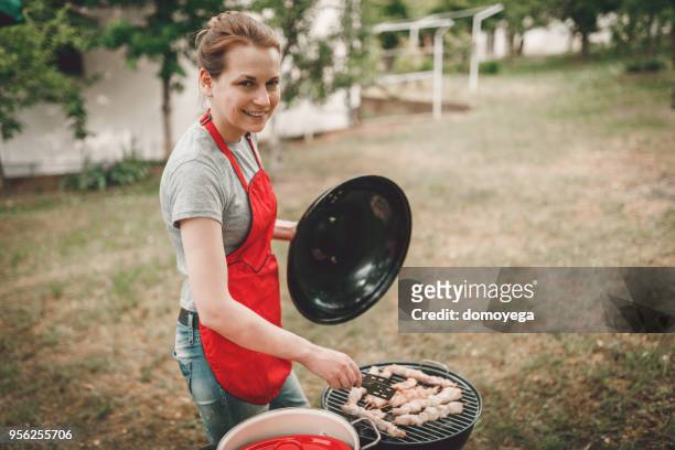 lächelnde frau eine gartenparty grillen vorbereiten - barbeque party woman stock-fotos und bilder