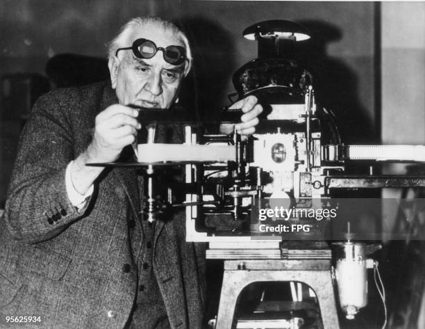 French pioneer filmmaker Louis Lumiere in Paris with projecting apparatus for his new anaglyph stereoscopic film system, 3rd July 1935. He is wearing...