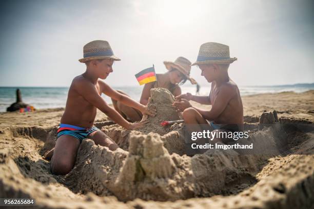 tre barn bygger ett sandslott på stranden - sand castle bildbanksfoton och bilder