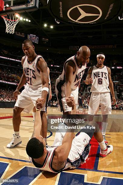 Devin Harris of the New Jersey Nets is helped up by teammates Bobby Simmons and Trenton Hassell during the game against the Cleveland Cavaliers on...