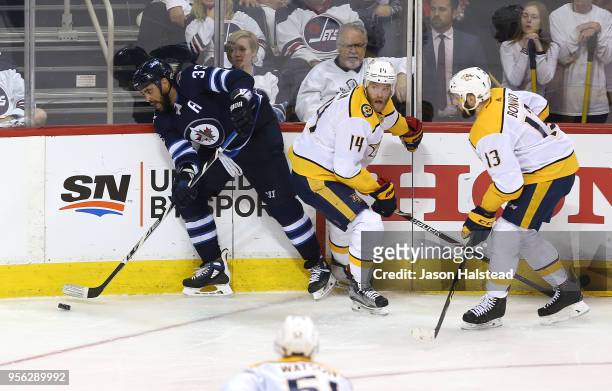 Dustin Byfuglien of the Winnipeg Jets tries to move the puck past Mattias Ekholm and Nick Bonino of the Nashville Predators in Game Six of the...