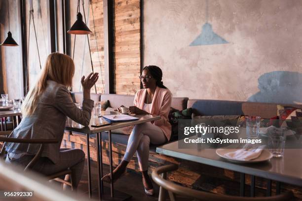 two business women having coffee break in high-end restaurant - cafe meeting stock pictures, royalty-free photos & images