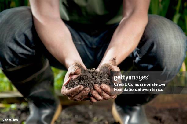 man wearing jeans and boots holding dirt in hands - green thumb 英語の慣用句 ストックフォトと画像