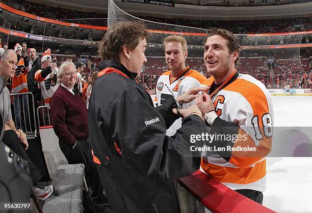 Mike Richards and Jeff Carter of the Philadelphia Flyers have their equipment worked on by equipment manager Derek Settlemyre during the pregame...