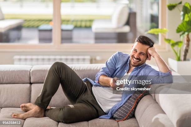 cheerful man changing channels while relaxing on sofa at home. - alter tv stock pictures, royalty-free photos & images