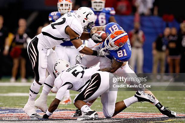 Dorian Davis of the Cincinnati Bearcats grabs the facemask of Aaron Hernandez of the Florida Gators during the Allstate Sugar Bowl at the Louisana...