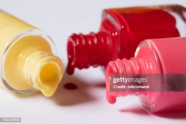 red, pink and yellow nail varnish spilling onto white background. - esmalte de uñas fotografías e imágenes de stock
