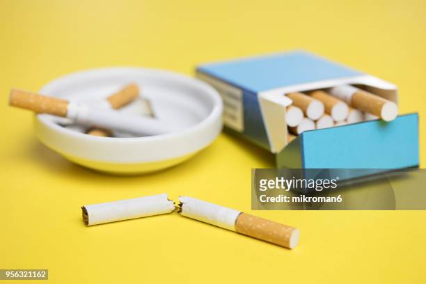 breaking the habit. cigarette box and cigarettes on yellow background - breaking habits ストックフォトと画像