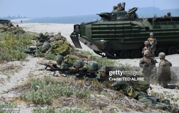Philippine and US marines take position next to assault amphibious vehicles as they simulate an amphibious landing as part of the annual joint...