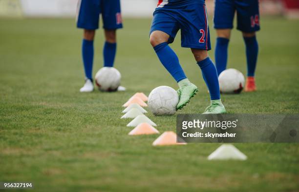 team of unrecognizable soccer players practicing dribbling with balls on a playing field. - dribbling stock pictures, royalty-free photos & images