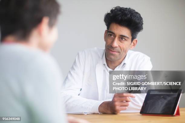 doctor discussing x-ray with patient - sigrid gombert - fotografias e filmes do acervo