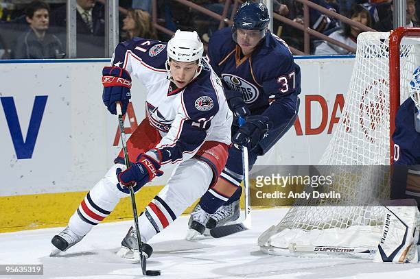 Alexandre Picard of the Columbus Blue Jackets carries the puck around the net under pressure from Denis Grebeshkov of the Edmonton Oilers at Rexall...