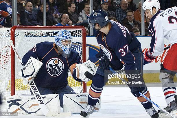 Devan Dubnyk of the Edmonton Oilers makes a save while Denis Grebeshkov protects the front of the net from a pressuring Alexandre Picard of the...