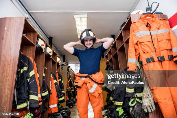 firefighter in a locker room - firefighter getting dressed stock pictures, royalty-free photos & images