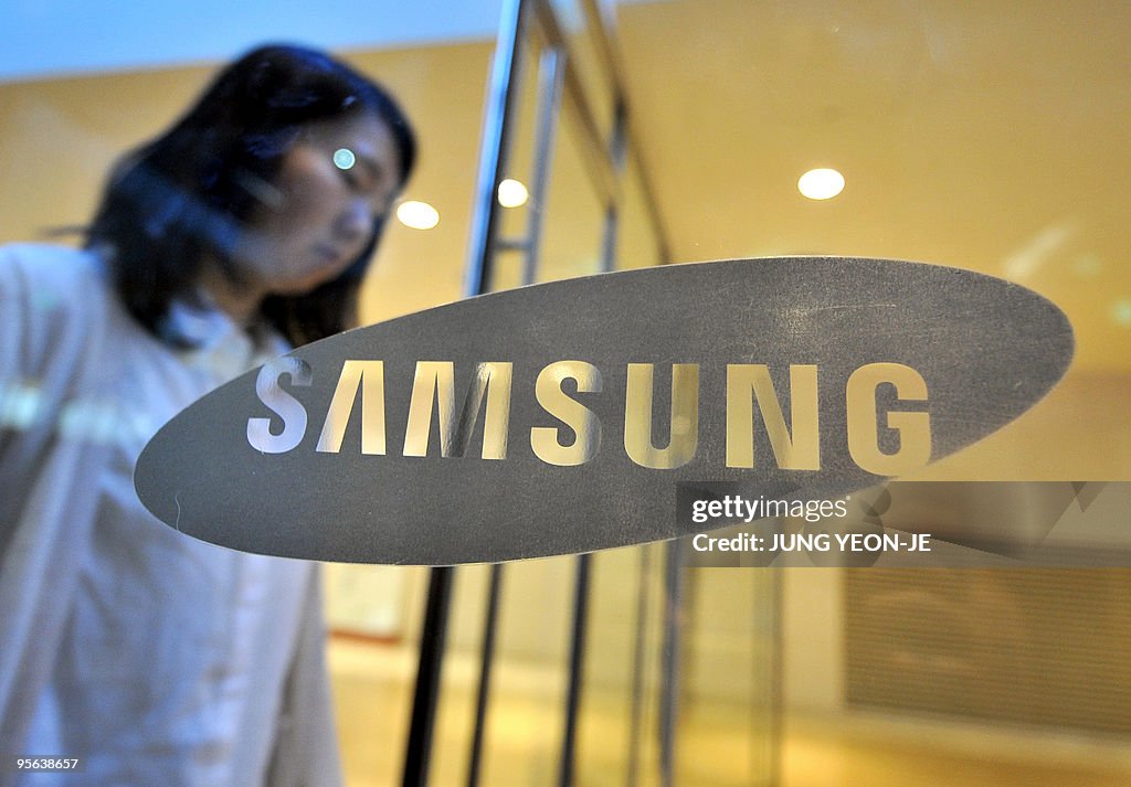 A woman walks past a logo of Samsung Ele