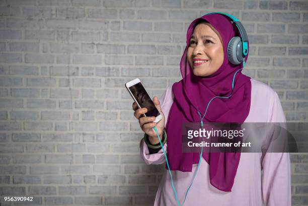 malay women enjoying music using headphone - malayan ethnicity stock pictures, royalty-free photos & images