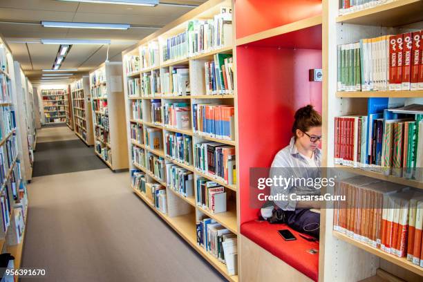 在圖書館使用手提電腦和手提電話的年輕��女子學生 - finland 個照片及圖片檔