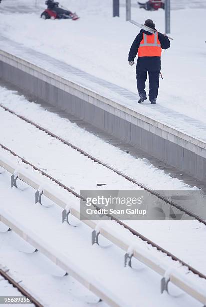 Worker carrying a snow shovel walks on a snow-covered platform at a commuter train station on January 8, 2010 in Berlin, Germany. Up to 40cm of new...