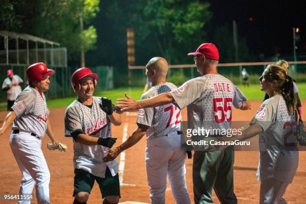 squadra softball congratulandosi con un giocatore - sport di squadra foto e immagini stock