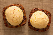 Pao de Queijo is a cheese bread ball from Brazil. Also known as Chipa, Pandebono and Pan de Yuca. Two snacks in basket over wood table, flat lay.
