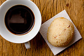 Pao de Queijo is a cheese bread ball from Brazil. Also known as Chipa, Pandebono and Pan de Yuca. Snack and espresso coffee on rustic wood, flat design.