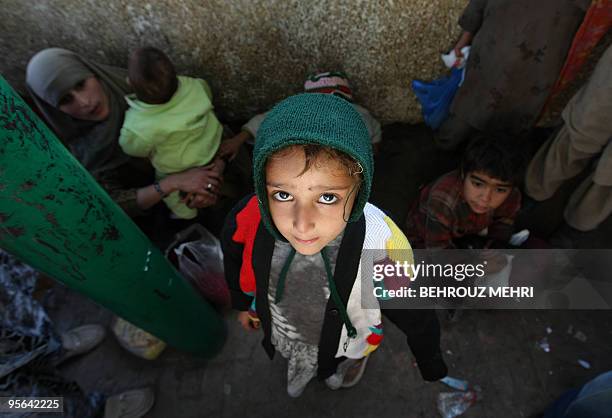 Young Pakistani poses after receiving donated food at the courtyard of the shrine of Sufi Saint Beri Imam in Islamabad on January 8, 2010. Bari Imam...