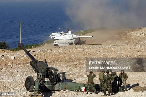 French army Leclerc tank with the United nations Iterim Forces in Lebanon roars next to Lebanese army troopers manning a 155mm Howitzer gun during a...