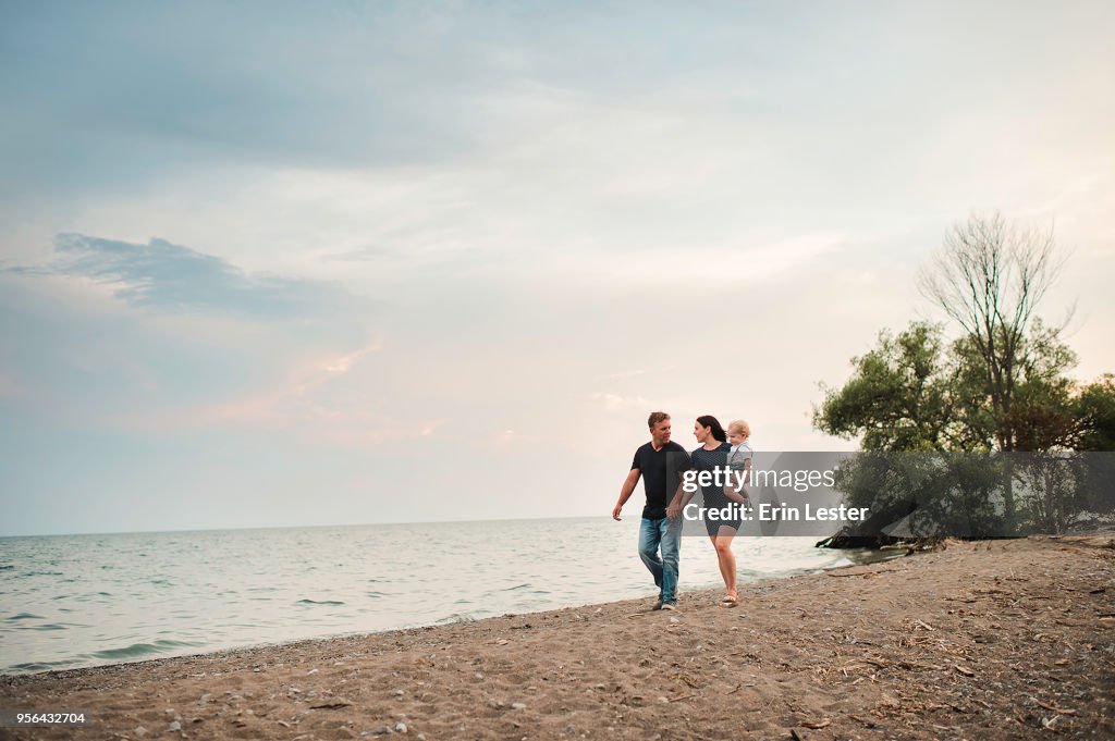 Pregnant couple strolling along beach with male toddler son, Lake Ontario, Canada