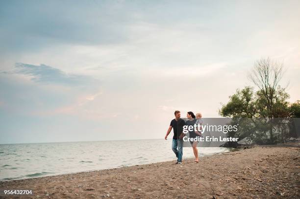 pregnant couple strolling along beach with male toddler son, lake ontario, canada - lake ontario stock pictures, royalty-free photos & images