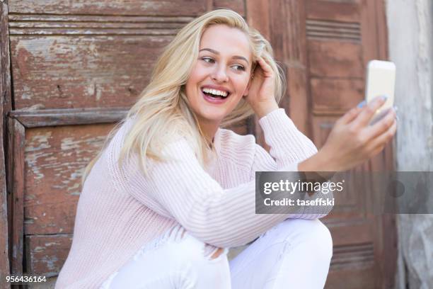 young woman sitting in front of door and making selfie - taseffski stock pictures, royalty-free photos & images