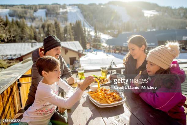 hispanic family having lunch next to ski runs at a winter ski resort in colorado. - holiday resort family sunshine stock pictures, royalty-free photos & images