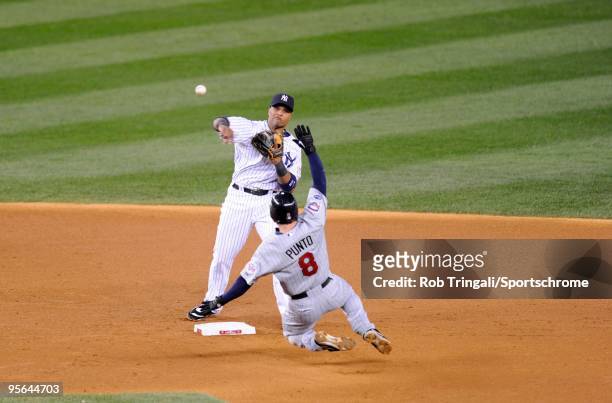Robinson Cano of the New York Yankees throws to first base over the sliding Nick Punto for the double play against the Minnesota Twins in Game One of...