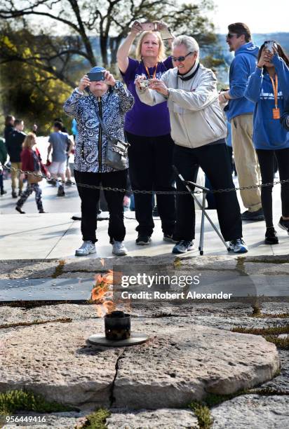 Visitors take photographs at the gravesite of former U.S. President John F. Kennedy and his wife, Jacqueline Kennedy Onassis, and the John F. Kennedy...