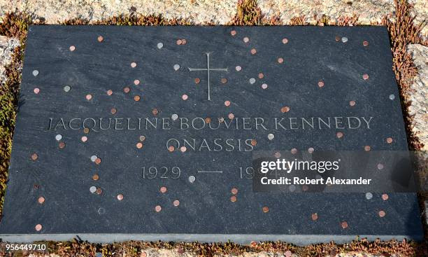 Coins tossed by visitors litter the grave of former First Lady Jacqueline Kennedy Onassis at Arlington National Cemetery near Washington, D.C.