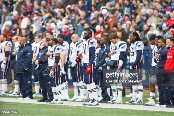 Randy Moss of the New England Patriots and teammates stand for the singing of the national anthem at the start of the game against the Buffalo Bills...