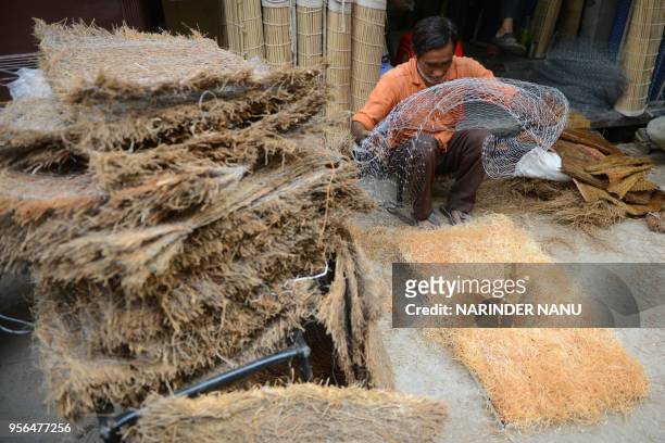 An Indian labourer prepares handmade air cooler pads at the roadside in Amritsar on May 9,2018.