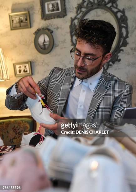 Syrian refugee Daniel Essa, former TV presenter in Damas, poses with the shoes he designed, in Villeneuve-d'Ascq, northern France on May 3, 2018. -...