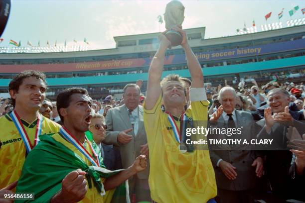 Brazilian captain Dunga holds aloft the FIFA World Cup trophy as Romario exults in front of Branco , after Brazil defeated Italy 3-2 in the shoot-out...