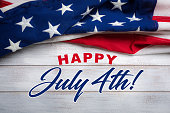 American flag on a white worn wooden background with July 4th Greeting
