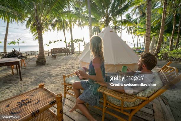 young couple relaxing in glamping campground in tropical scenery - luxury tent stock pictures, royalty-free photos & images