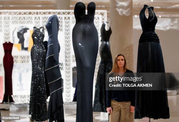 Gallery assistant poses for a photograph with dresses by Tunisian-born designer Azzedine Alaia, in a collection entitled "Black Silhouette", ahead of...