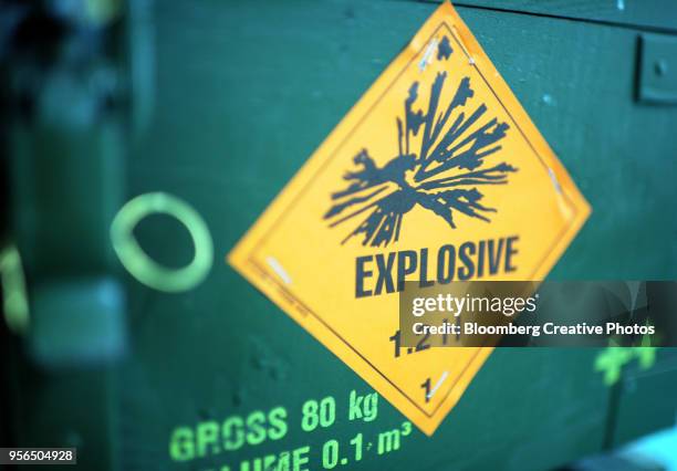 a warning sign reading "explosive" sits on a case of artillery munitions - explosive stock-fotos und bilder