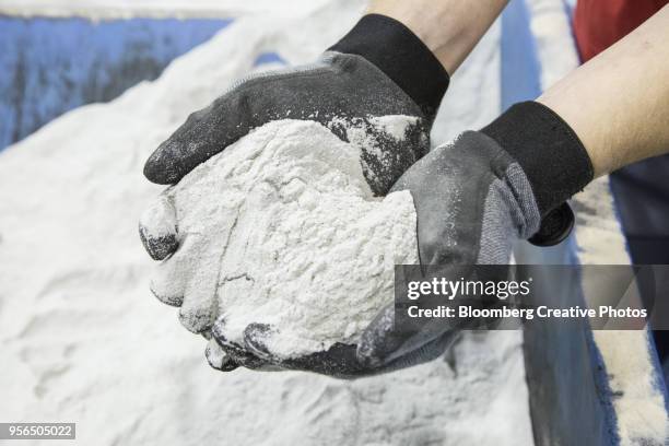 an employee holds silica sand, the base material for making 3-d printing molds - silicaat stockfoto's en -beelden