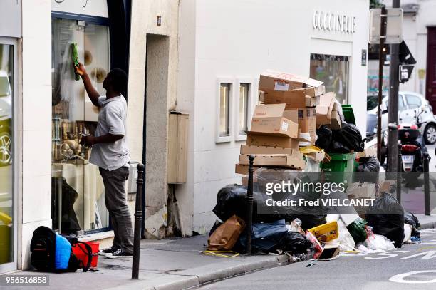 Poubelles sur le trottoir débordant de déchets devant un magasin 'Coccinelle' suite à la grève des éboueurs, 10 juin 2016, Paris, France.