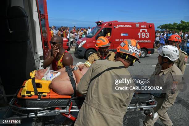 Emergency services and lifeguards attend an injured man, who was involved in a helicopter crash in Barra de Tijuca, Rio de Janeiro, Brazil, on May 9,...