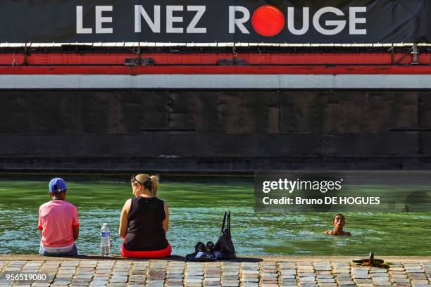 Un homme nageant dans le Canal de l'Ourcq par forte chaleur le 8 Juillet 2017, Paris, France.